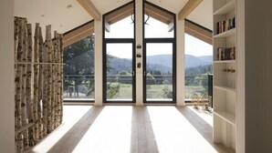 A spacious room with large windows, a wooden floor, and a bookshelf. - Schweizerhaus Alpirsbach (Alpirsbach)