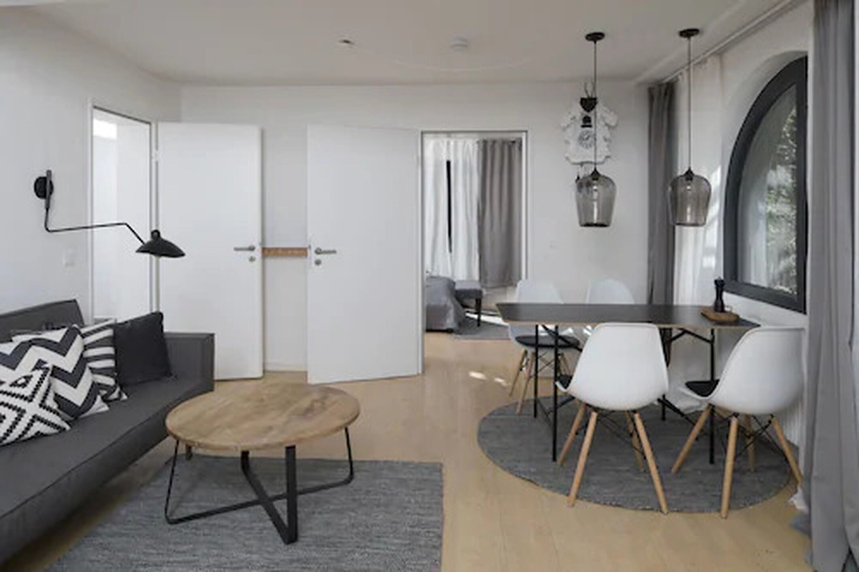 Uma sala de estar moderna com sofá, mesa de centro e área de refeições com cadeiras.