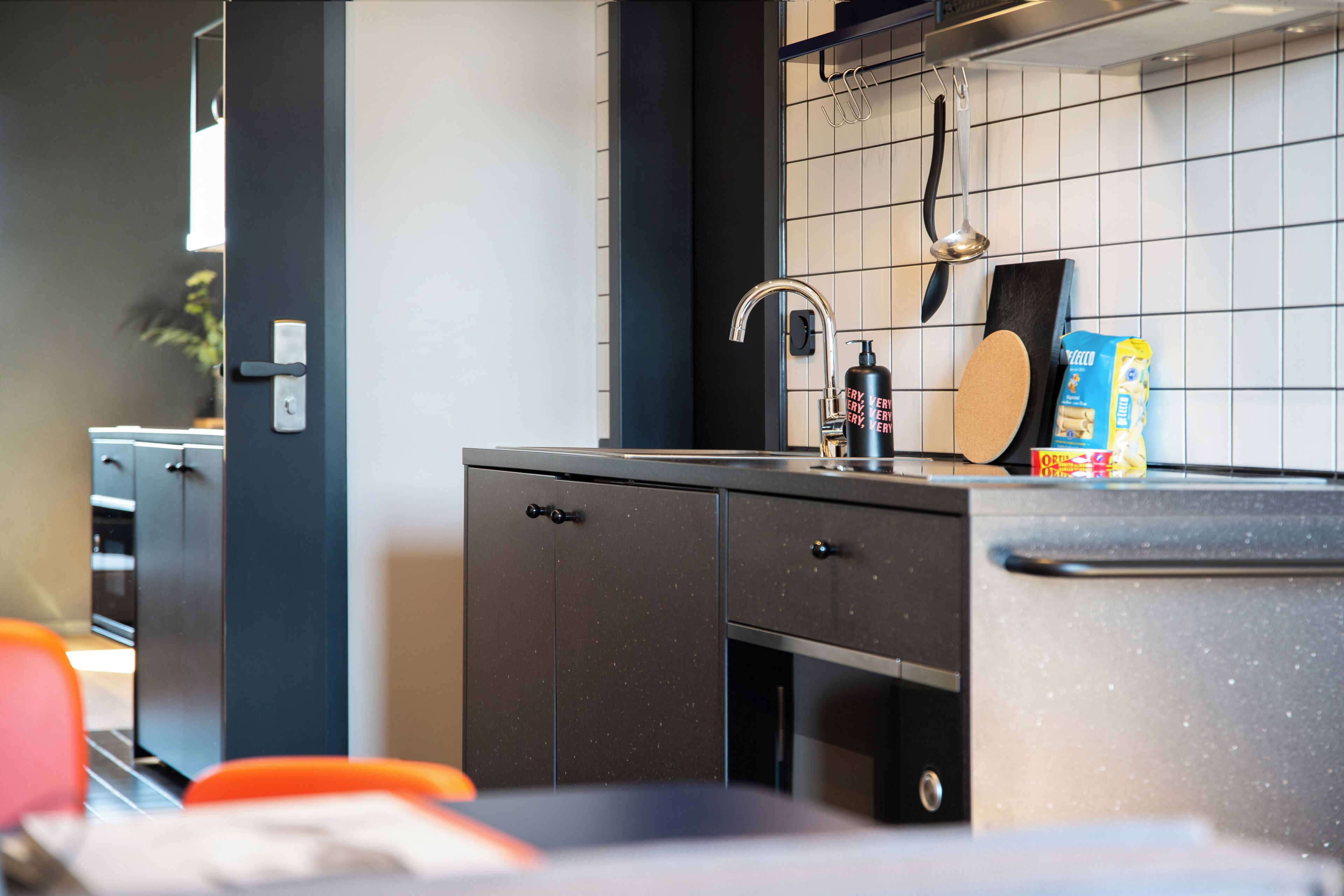 A modern kitchen with a black countertop, a stainless steel sink, and a kettle.