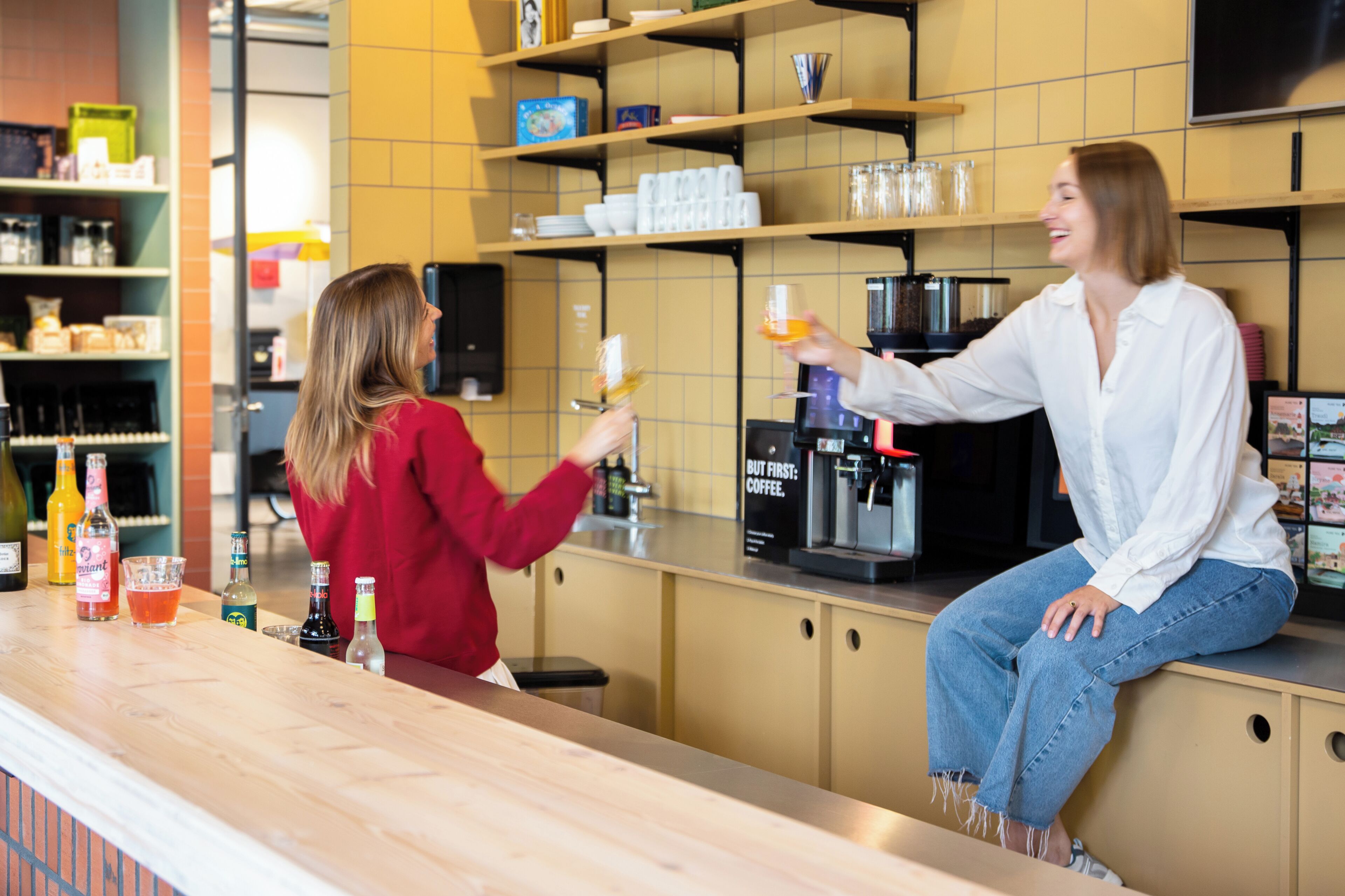 Zona de bar con una máquina de café, estantes con varios artículos y una barra con botellas.