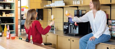 Een bar met een koffieapparaat, planken met diverse artikelen en een toonbank met flessen.
