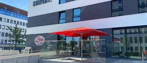 A modern building with a glass facade and a red umbrella outside.