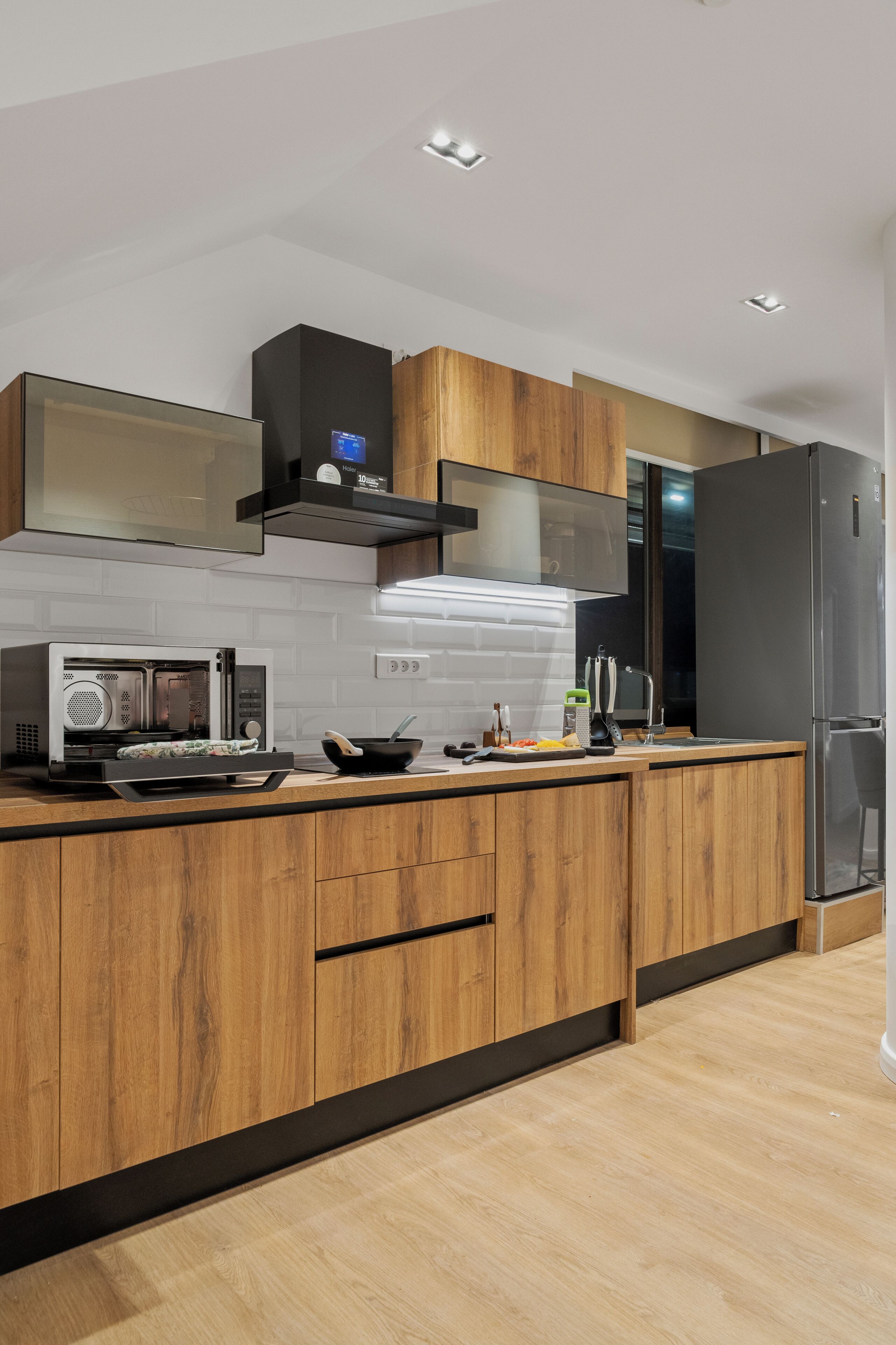 Una cucina moderna con mobili in legno, un forno a microonde integrato e un frigorifero in acciaio inossidabile.