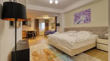 A modern hotel room with a large bed, a desk, and a dining area.
