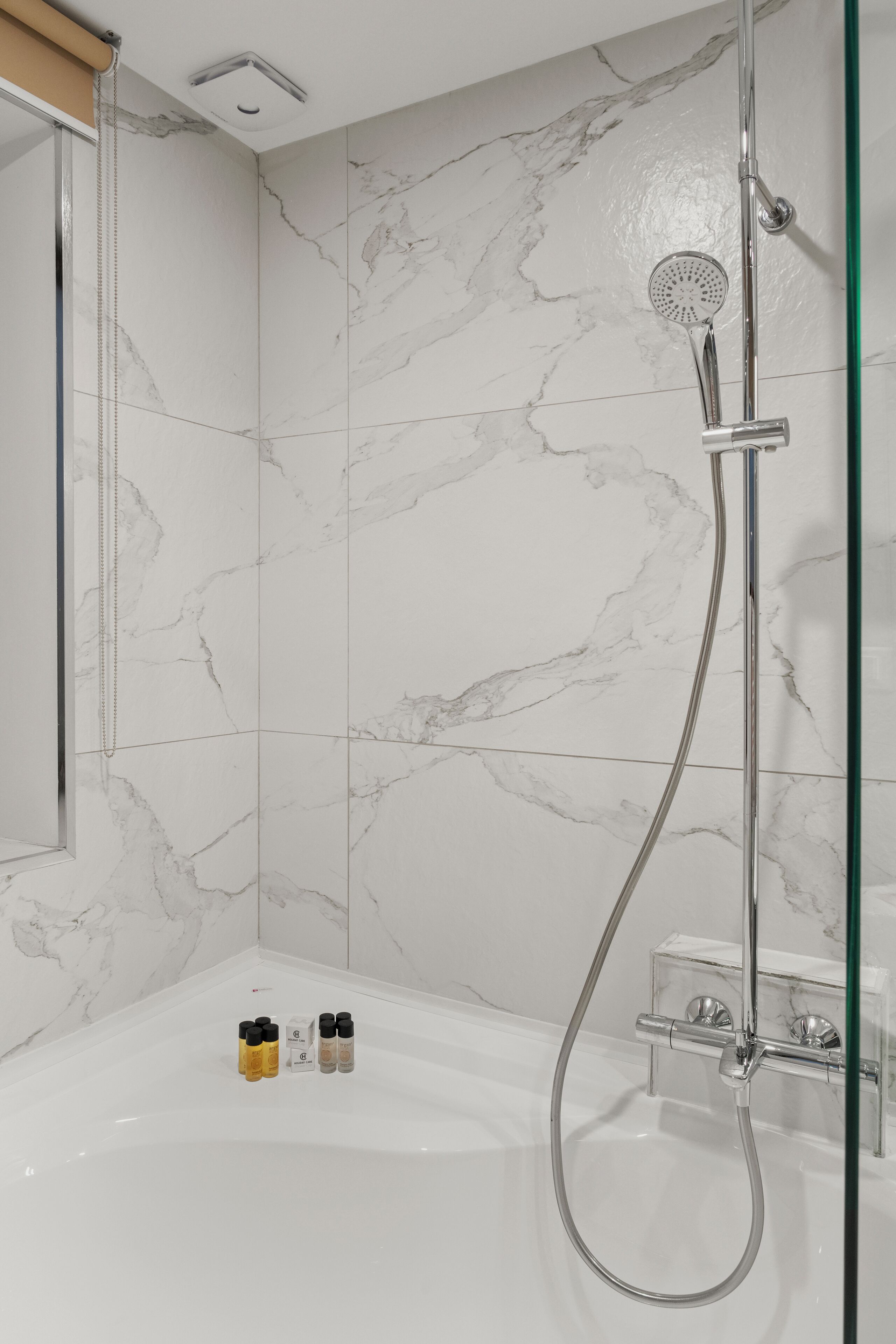 A modern bathroom with a shower, a bathtub, and marble tiles.