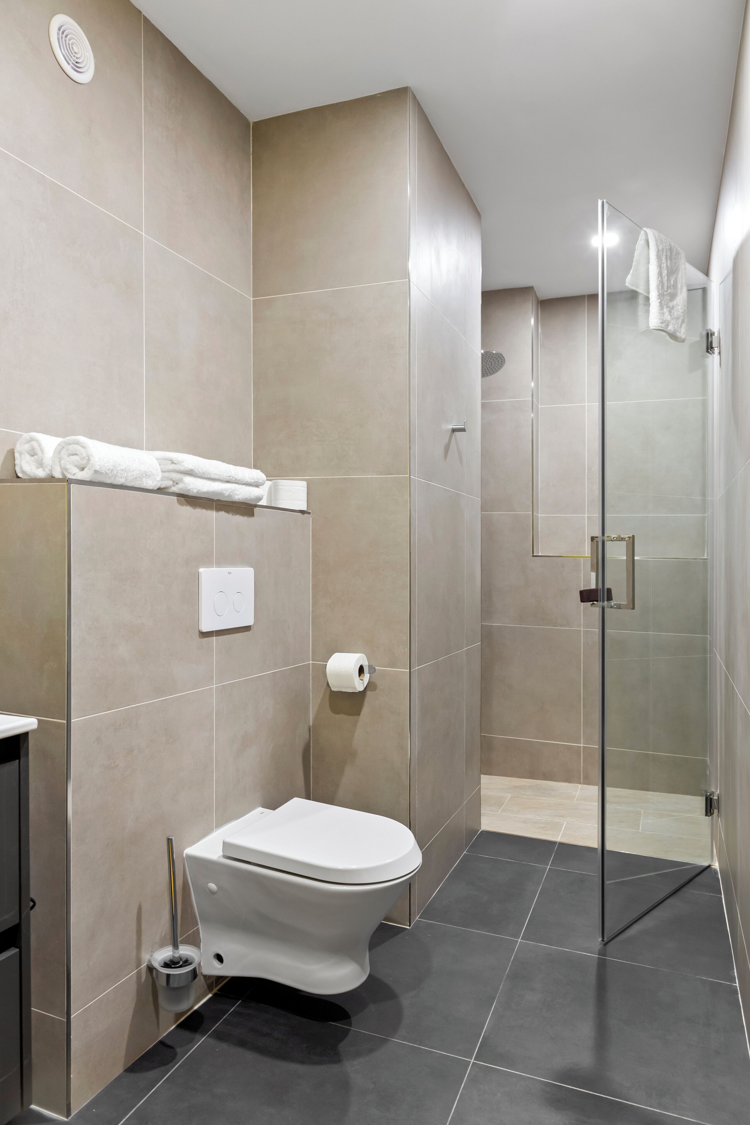 Un baño moderno con inodoro, cabina de ducha de vidrio y barra para toallas.