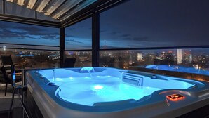 A hot tub with a city view, a chair, and a table.