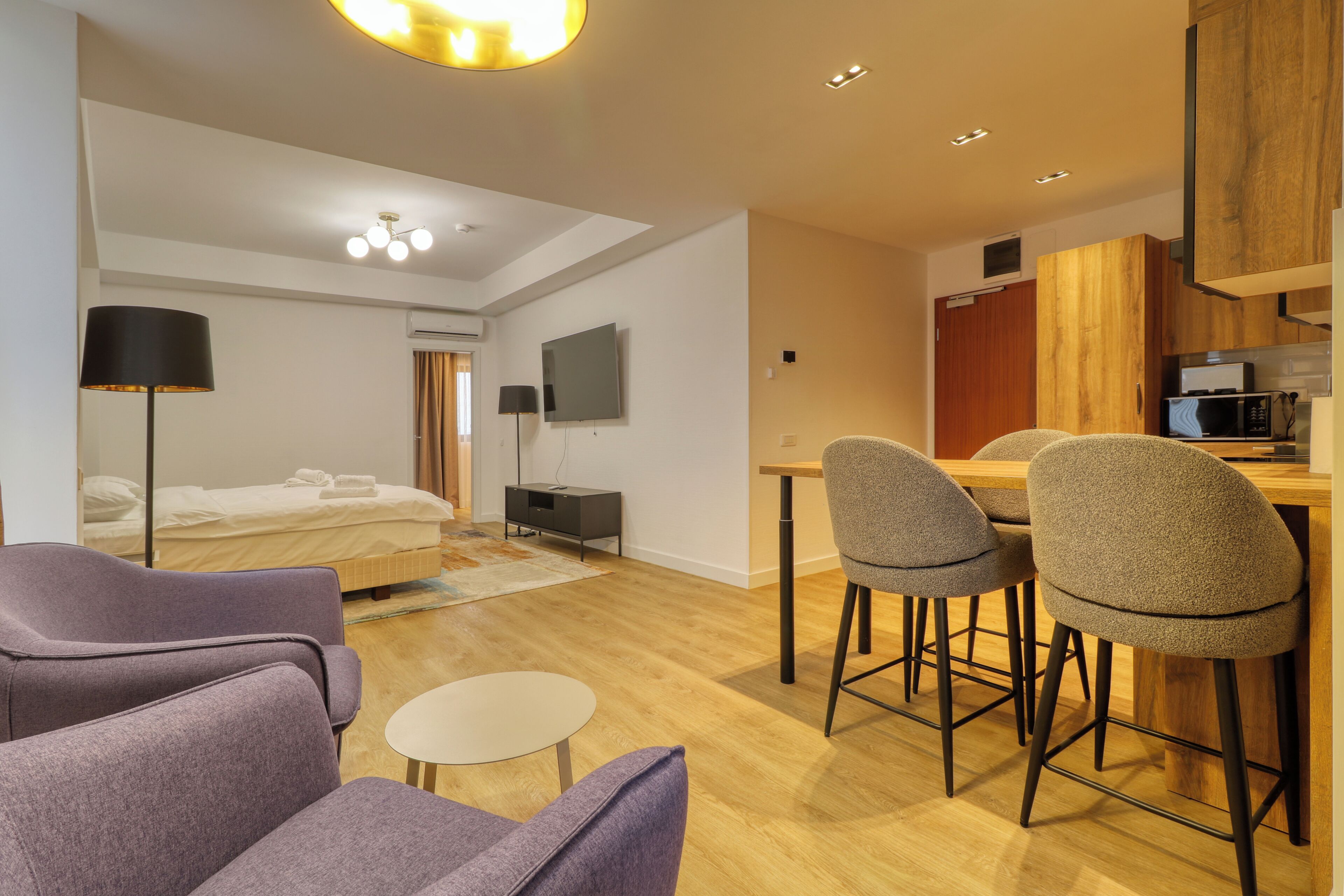 Een moderne hotelkamer met een bed, een bureau, een stoel, een kleine tafel en een televisie.