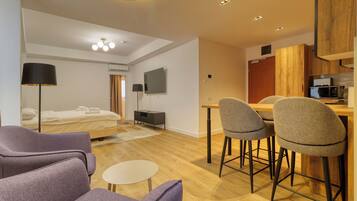 Een moderne hotelkamer met een bed, een bureau, een stoel, een kleine tafel en een televisie.