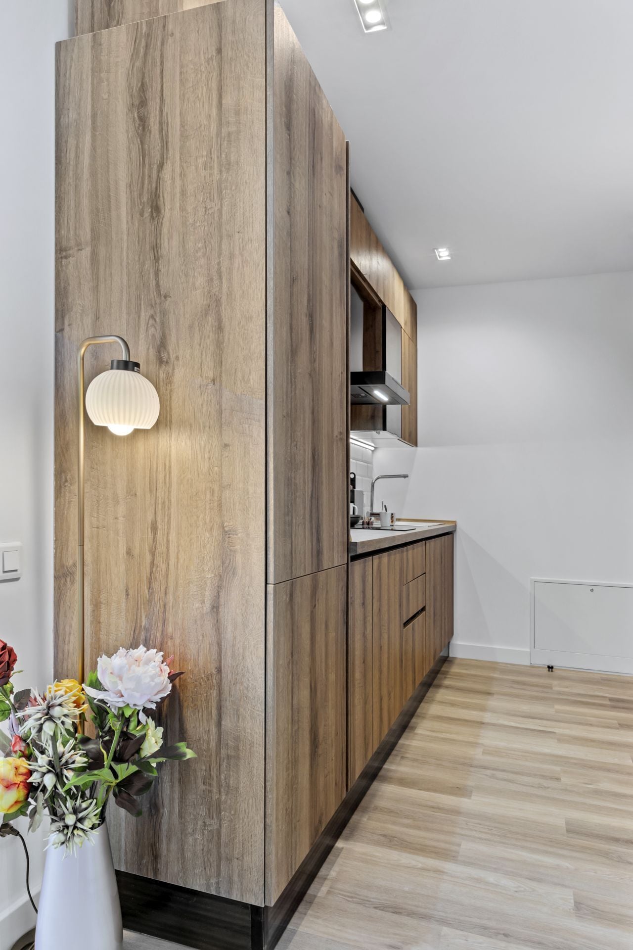 Una cocina moderna con armarios de madera, horno empotrado y una lámpara.