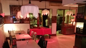 A dining area with tables and chairs, a kitchen area, and a counter with a sign. - Hotel Sibilla Residence (Pozzuoli)