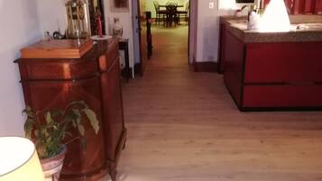 Un estrecho pasillo con suelo de madera que conduce a un comedor con una mesa y sillas.
