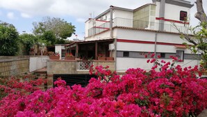 A modern building with a balcony and a garden with vibrant pink flowers. - Hotel Sibilla Residence (Pozzuoli)