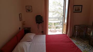Una habitación con una cama, una mesita con sillas, un televisor y una ventana con cortinas.
