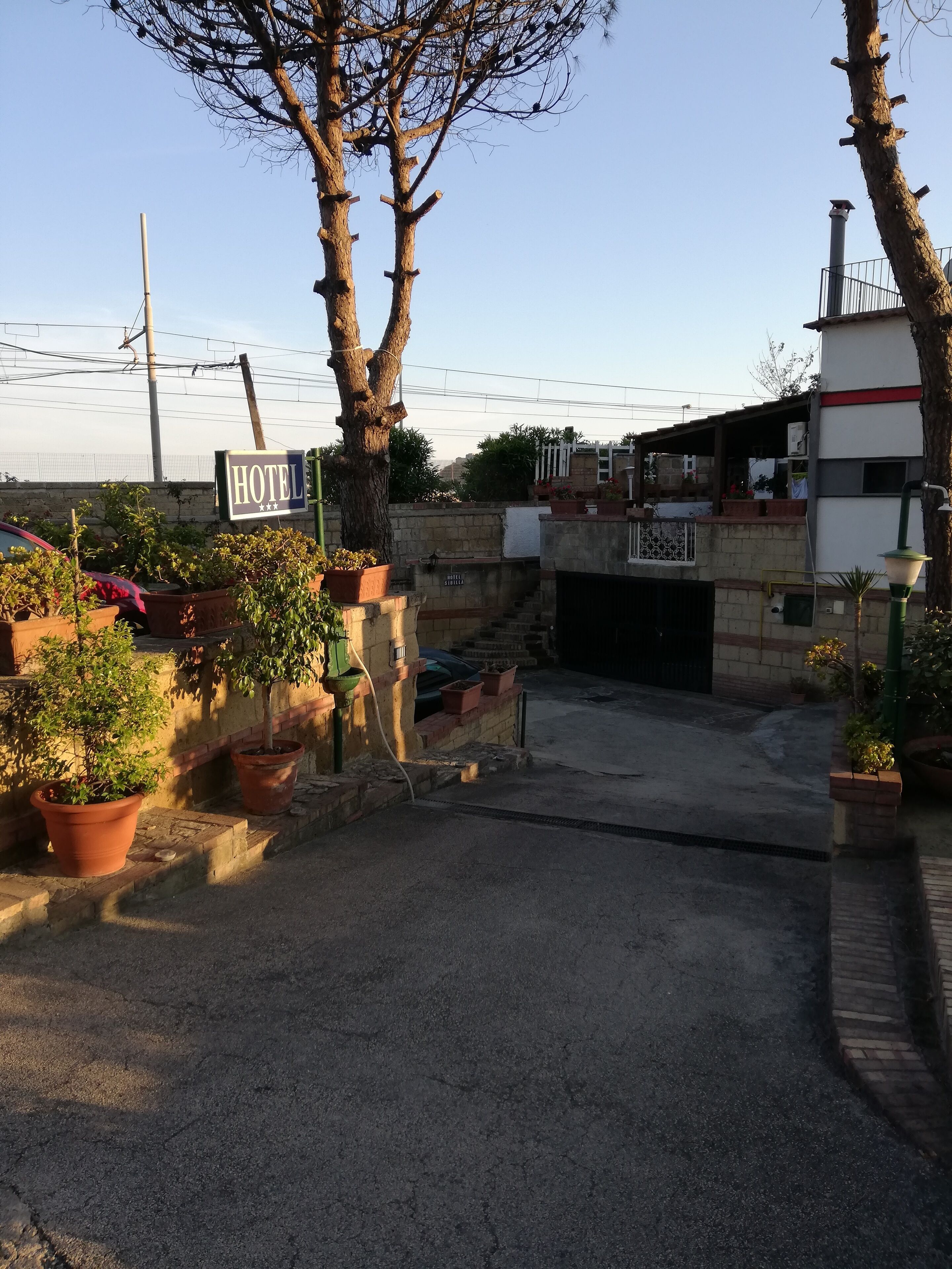 L’entrée d’un hôtel, avec une enseigne, des plantes en pot et un mur de pierre.