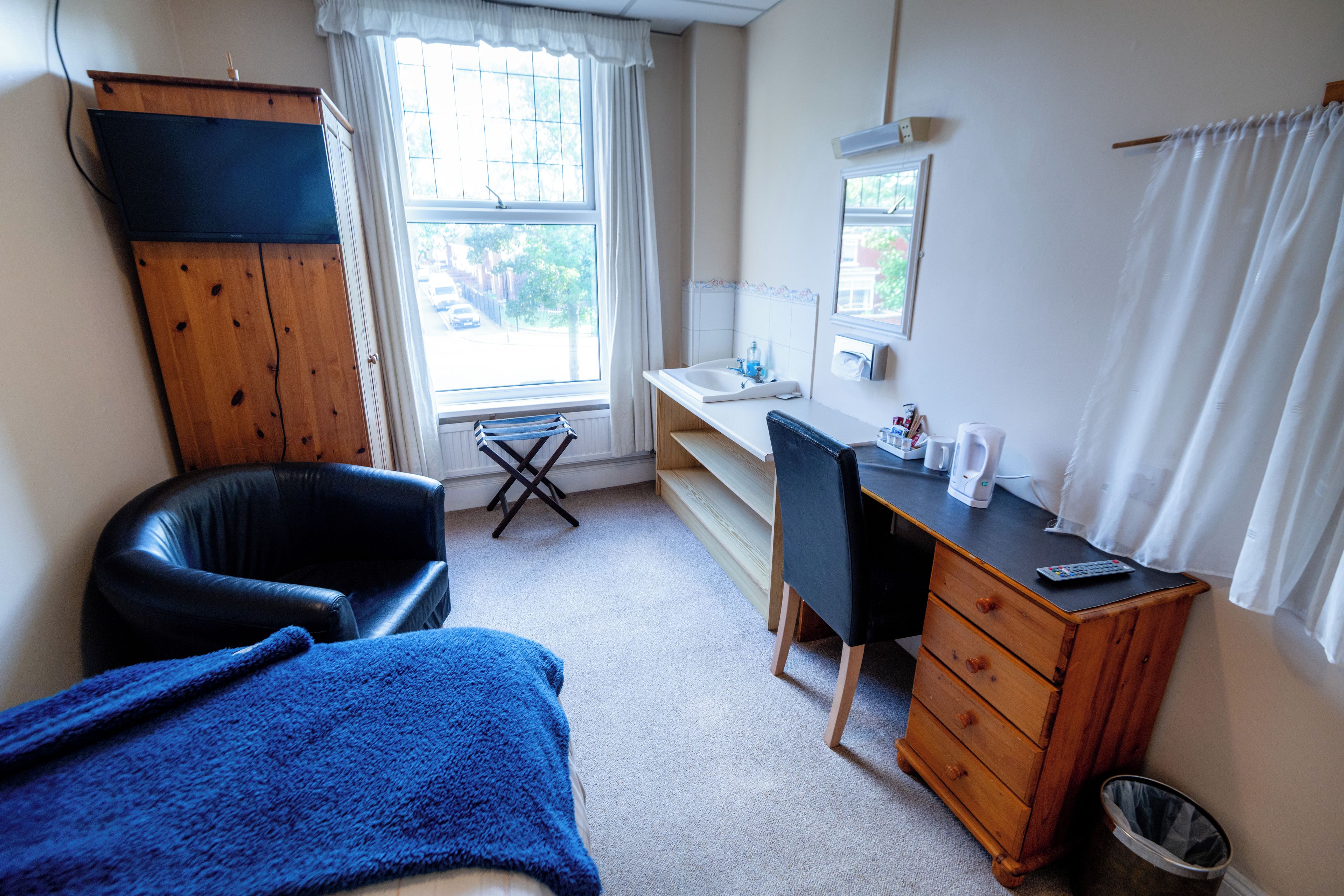 A room with a bed, a desk, a chair, a wardrobe, a window, and a radiator.