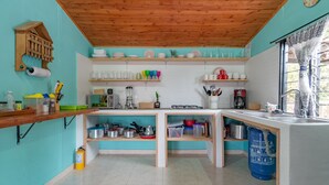 Una cocina con estantes de madera, estufa a gas y dispensador de agua azul.