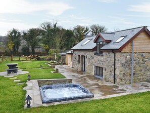 Une maison en pierre avec un jacuzzi, une terrasse et une clôture en bois.