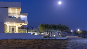 Een modern huis met een balkon, een pad en een boom.