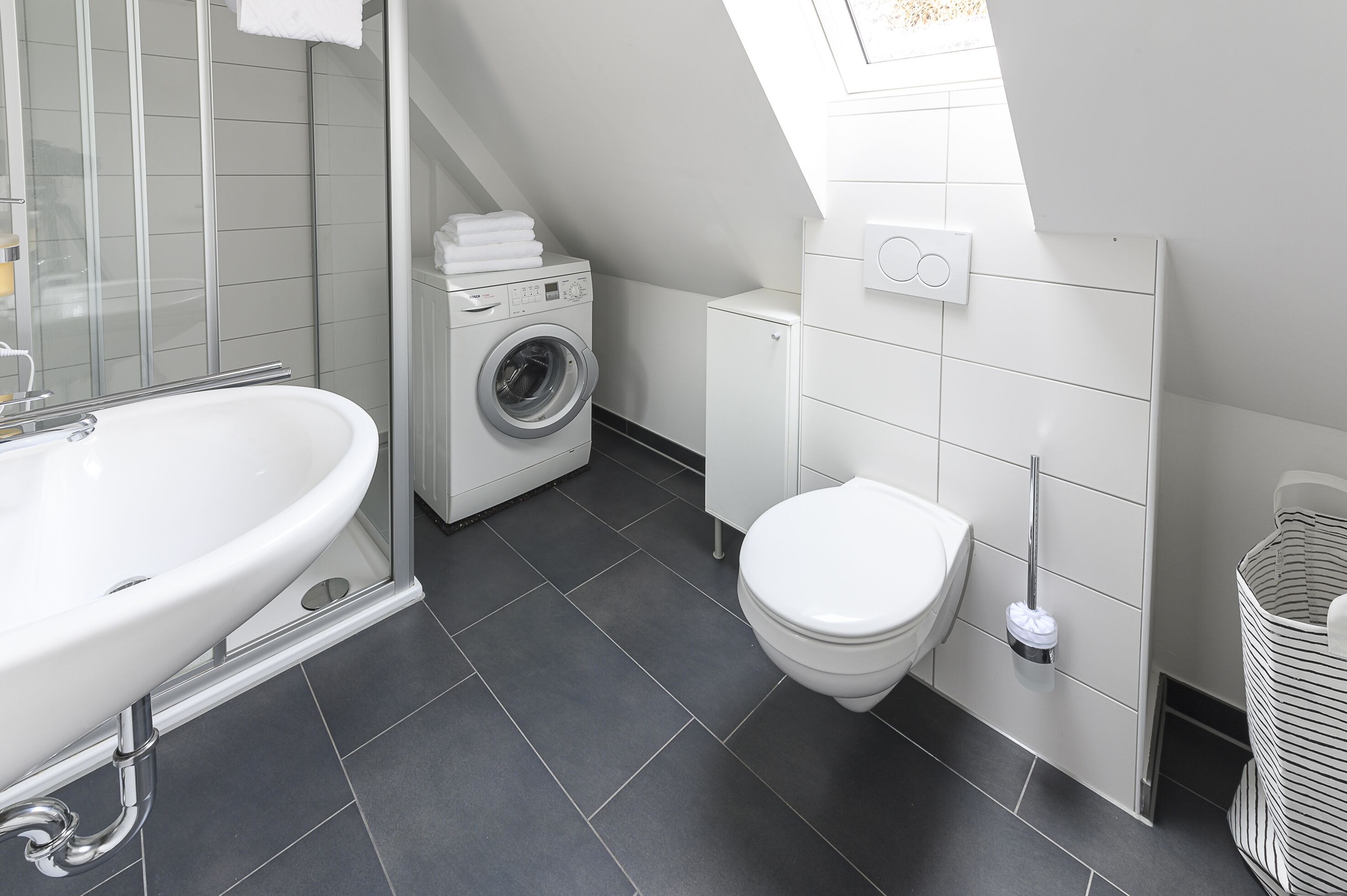 Un bagno moderno con una vasca da bagno freestanding, una lavatrice integrata, un WC e un box doccia.