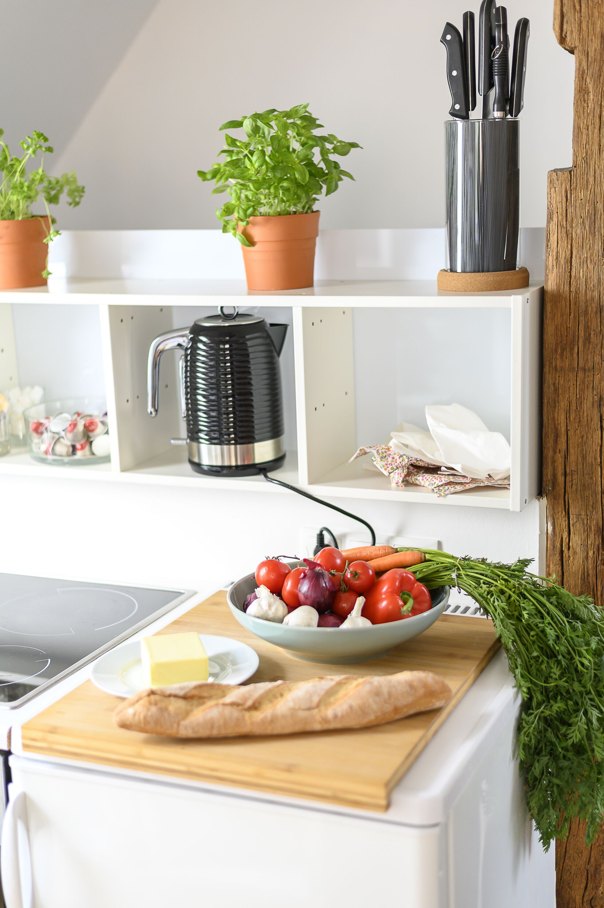 Une cuisine équipée d’une planche à découper, d’un saladier rempli de légumes, d’une miche de pain et d’une machine à café.