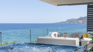 Un bain à remous avec vue sur la mer et les montagnes, des meubles en osier et un espace abrité.