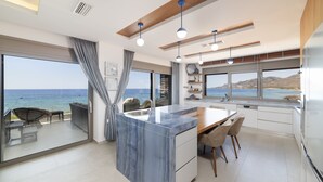 Une cuisine moderne dotée d’un grand îlot central, d’un coin repas et offrant une vue sur la mer.