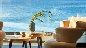 Un salon moderne avec vue sur l’océan, comprenant un canapé, une table basse et une plante décorative.