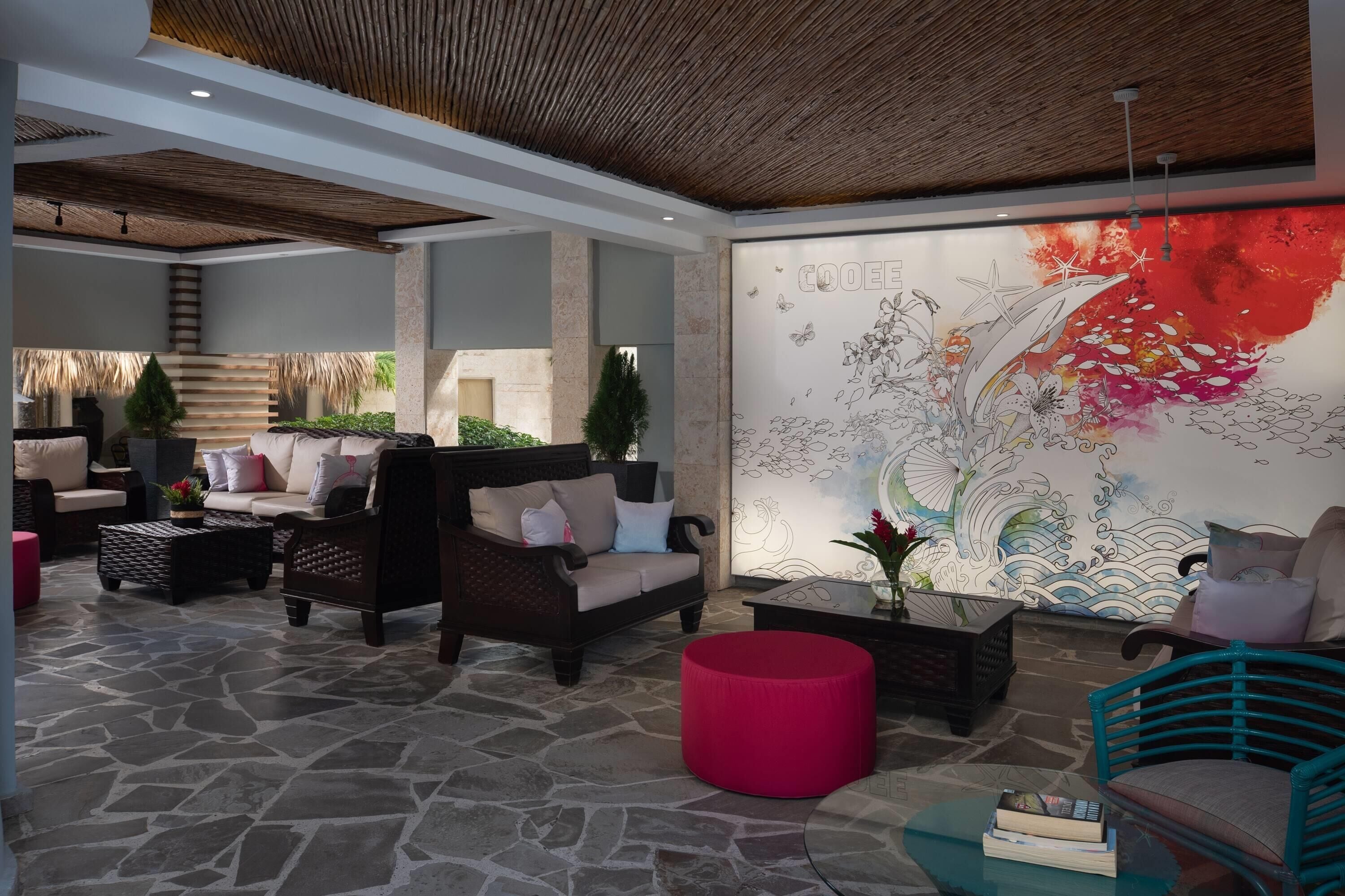 Un espace de détente moderne avec un sol en pierre, des sièges confortables et une grande fresque murale.
