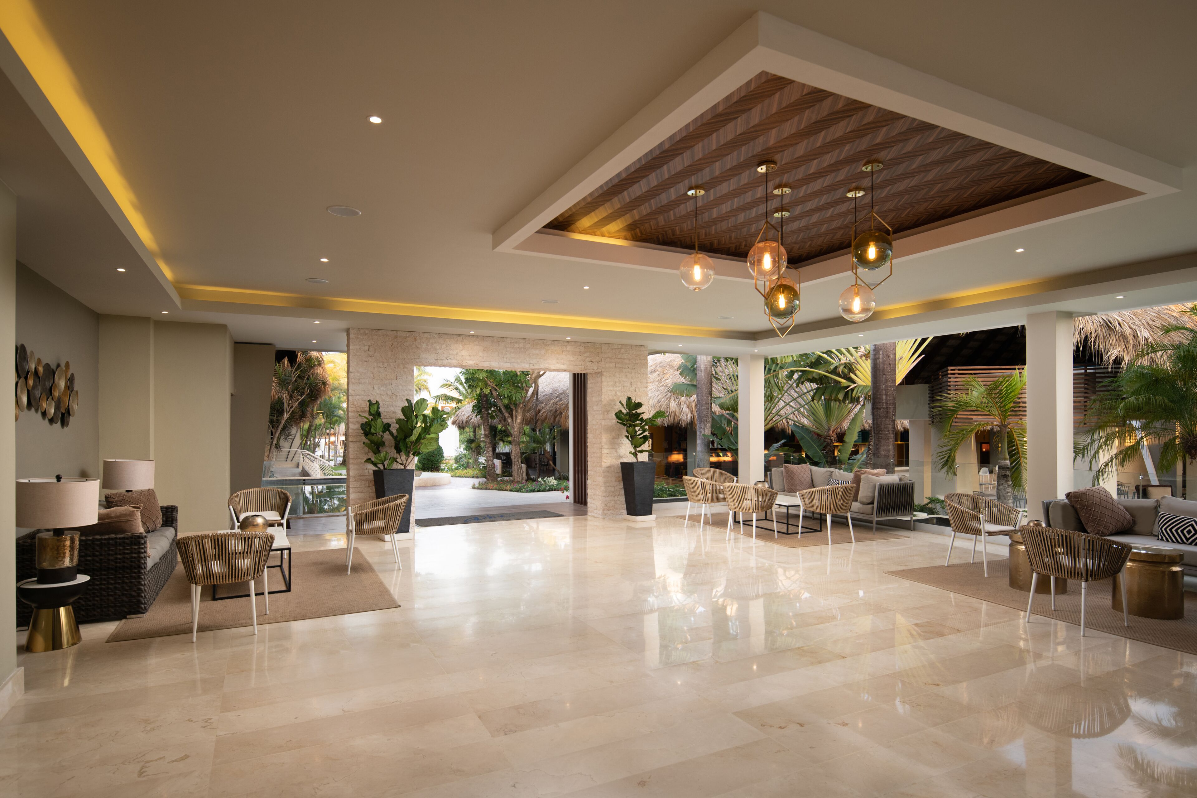 Un lobby amplio con techo alto, luminarias modernas y una variedad de zonas de estar con sofás y sillones.
