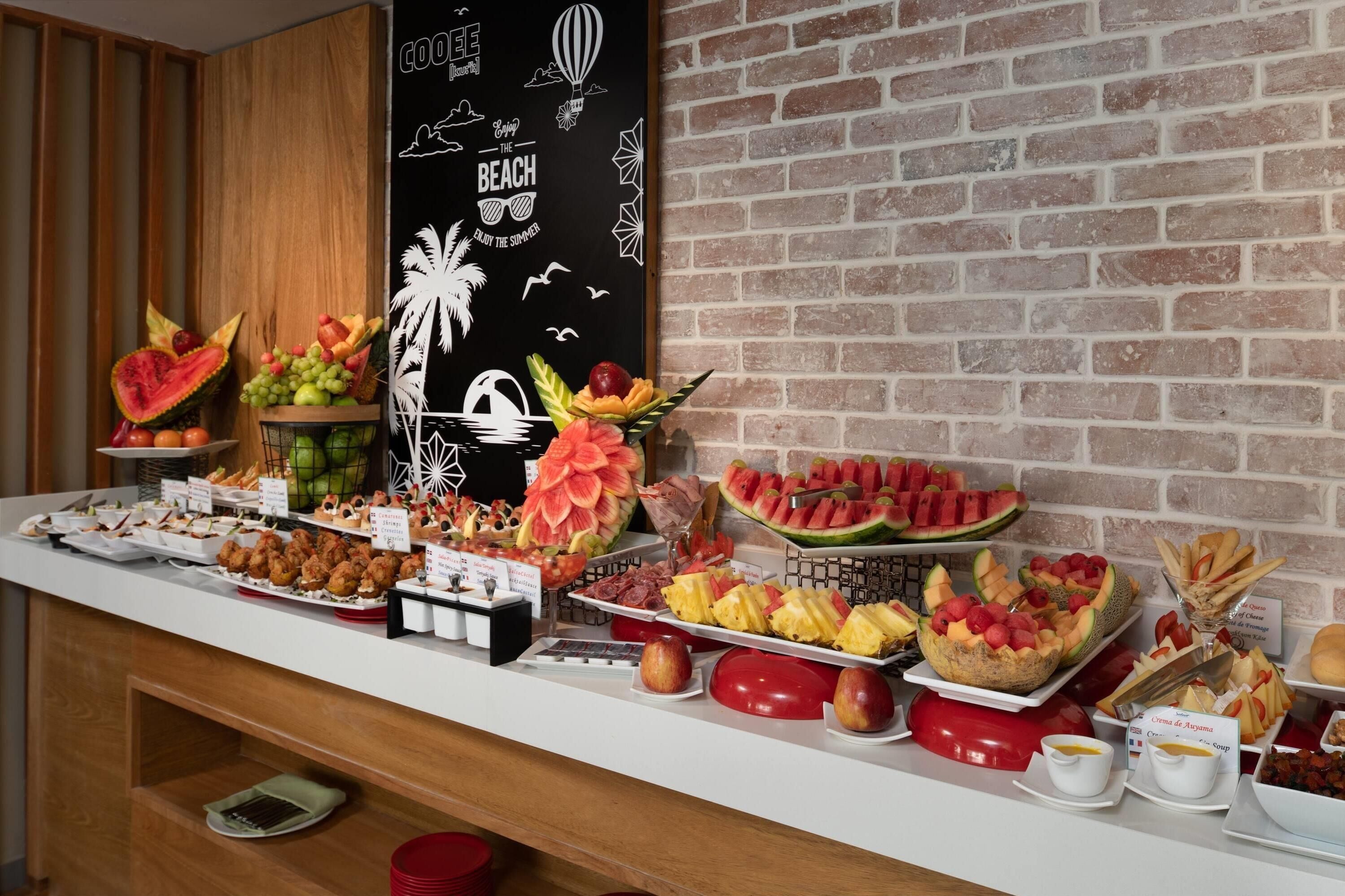 A buffet with various fruits, pastries, and desserts.