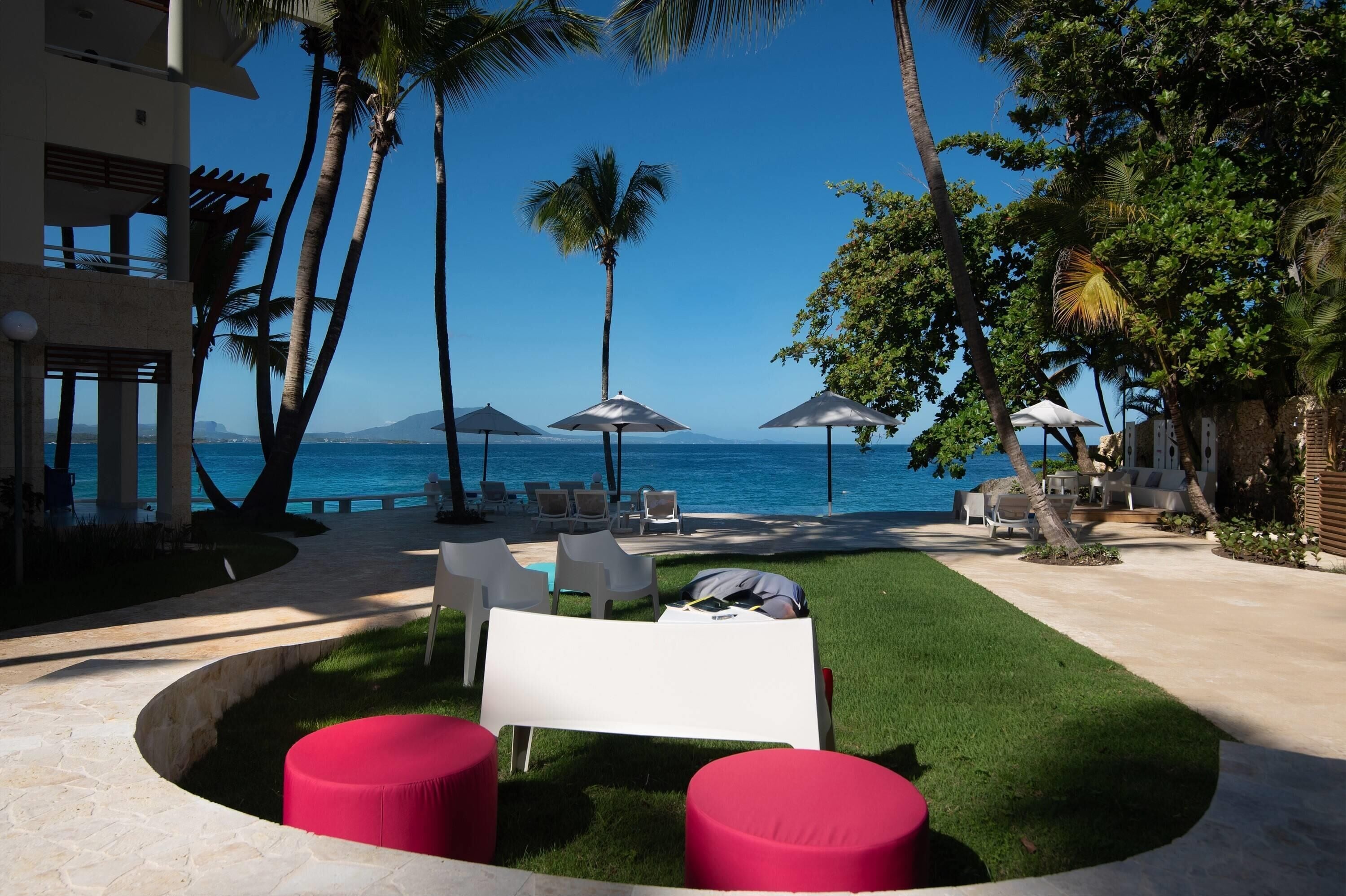 A resort with a pool area, outdoor seating, and a view of the ocean.
