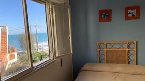 A bedroom with a large window, a bed, and two wall-mounted artworks. - Hotel Ristorante Il Triangolo (Augusta)