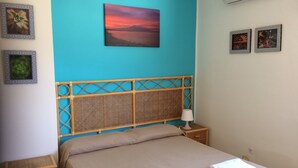 A bedroom with a bed, a nightstand, a lamp, and wall art. - Hotel Ristorante Il Triangolo (Augusta)