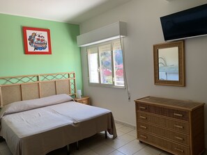 A bedroom with a bed, a dresser, a TV, a window, and a framed picture on the wall. - Hotel Ristorante Il Triangolo (Augusta)