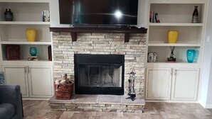 A living room with a fireplace, a flat-screen TV mounted above it, and a sofa. - A modern country place (Snellville)