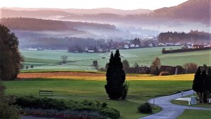 A rural landscape with a winding road, a bench, and a row of houses in the distance. - TIME OUT at the edge of the forest, peace and enjoyment of nature, A1 media box / TV Plus, garden / pets (Weinitzen)