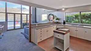 A modern kitchen with large windows, a gas stove, and a sink.