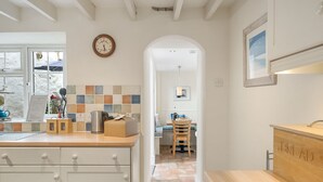 Una cocina moderna con encimera de madera, cafetera y zona para pan.
