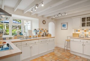A kitchen with white cabinets, a tiled backsplash, and a window with a view of greenery.