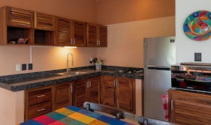 A kitchen with wooden cabinets, a stainless steel refrigerator, a sink, and a colorful tablecloth. - WATERFRONT PENTHOUSE 75m2 WITH PRIVATE PALAPA TERRACE- INFINITY POOL (Barra de Navidad)
