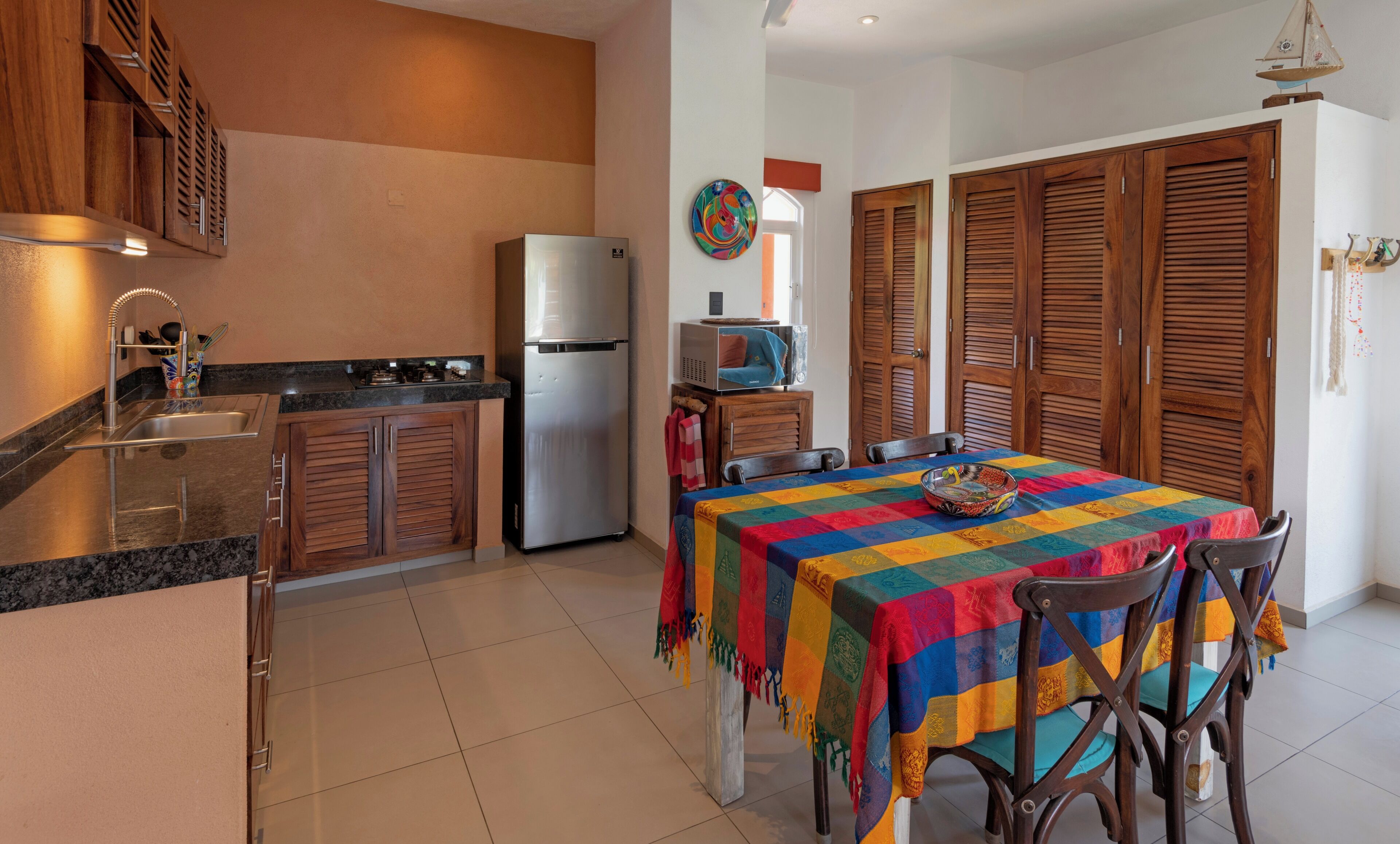 Une cuisine équipée d’un réfrigérateur, d’une cuisinière et de meubles de rangement en bois.