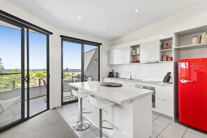 Une cuisine moderne dotée d’un grand îlot central, de meubles blancs et d’un réfrigérateur rouge.