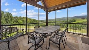 Un espace extérieur abrité, doté d’une table et de chaises, offrant une vue sur un paysage pittoresque.