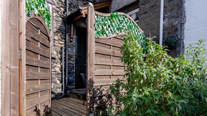 A wooden door with a stone wall, a wooden deck, and potted plants. - 2 bedroom accommodation in Windermere (Windermere)