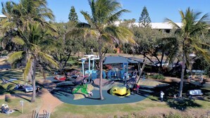 Un parque infantil con toboganes y columpios rodeado de palmeras.