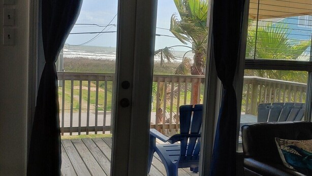 A room with a view of a wooden deck, a chair, and a table. - Ocean Views & Steps to Car-Free Beach (Galveston)