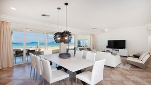 Un salon moderne comprenant un coin repas, un téléviseur et une vue sur la plage.