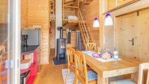 Et interiør af en træhytte med et køkken, spiseplads og en trappe, der fører op til et loft.