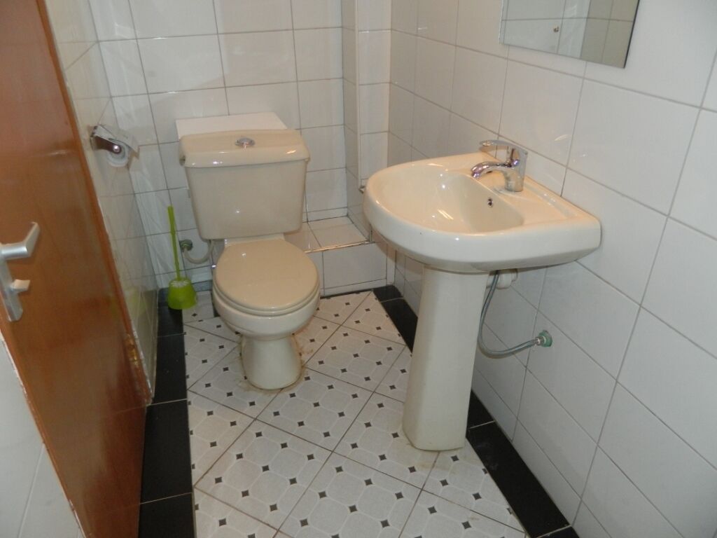 Un baño con inodoro, lavamanos y piso de baldosas.